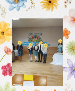 Uczniowie z dyplomami podczas szkolnego konkursu, stojący na sali.